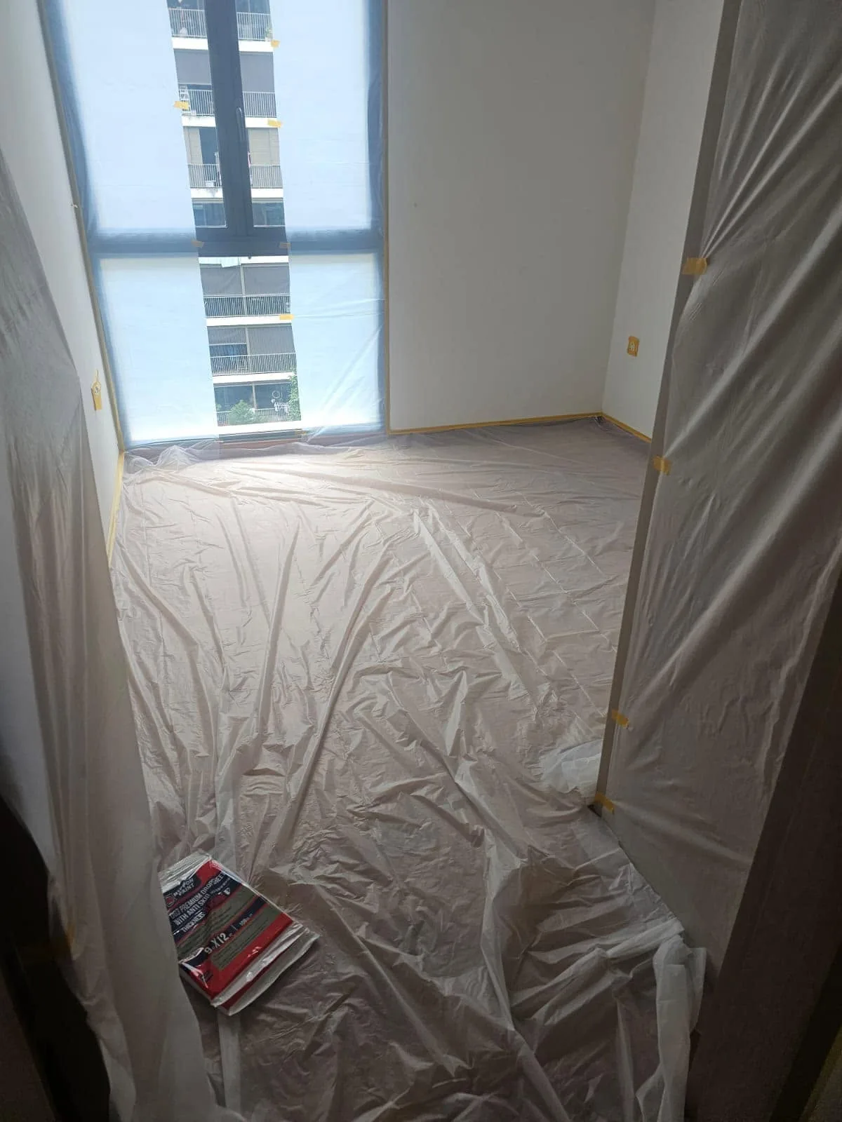 A&J Painting site setup showing plastic floor protection and masked window frames before painting